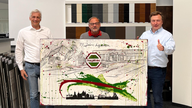 Hartmut Goldboom, Direktor Gesellschafterentwicklung der Hagebau (r.), übergibt den Mayrose-Geschäftsführern Andreas Augenthaler (l.) und Wolfgang Zink ein Geschenk zum 50. Hagebau-Jubiläum. Das individuell gemalte Bild zeigt Mayrose-Standorte von früher und heute.&nbsp;