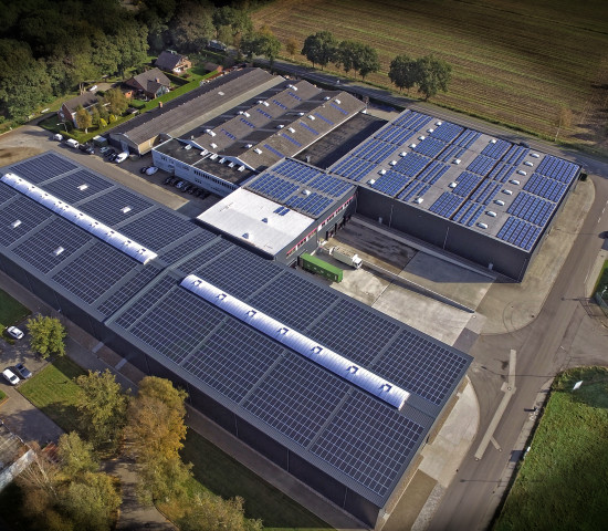 Die Vogelperspektive macht die Dimensionen der Erweiterung in Westerstede erkennbar. Vorne im Bild ist der 5.600 m² große Neubau erkennbar; das Dach ist fast vollständig von einer Photovoltaikanlage bedeckt.