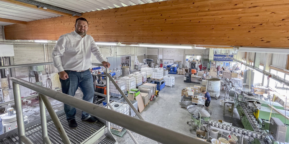 Tobias Gölz schaut oben von den Mischbehältern in die Produktionshalle mit Perlmühle (hinten) &nbsp;und der pneumatischen Doppelkopf-Abfüllmaschine (rechts).